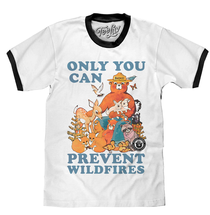 Watercolor graphic of Smokey Bear surrounded by forest animals and the 'Only You Can Prevent Wildfires' text printed on a white ringer tee with black collar and sleeve ribbing.