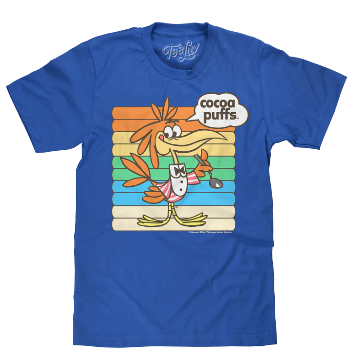 Officially licensed royal blue General Mills Cocoa Puffs cereal shirt featuring Sonny the Cuckoo Bird against a colorful graphic background.